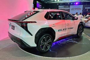 Toyota bZ4X at 2022 ExpoMovilidad Costa Rica, white with black accents, ELECTRIC text on side, rear and side view on blue-lit platform