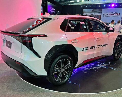 Toyota bZ4X at 2022 ExpoMovilidad Costa Rica, white with black accents, ELECTRIC text on side, rear and side view on blue-lit platform