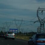 Highway with cars and high-voltage power transmission lines near Hillsboro, Oregon, illustrating U.S. infrastructure amid rising electricity demand.
