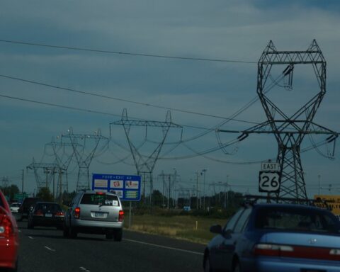 Highway with cars and high-voltage power transmission lines near Hillsboro, Oregon, illustrating U.S. infrastructure amid rising electricity demand.