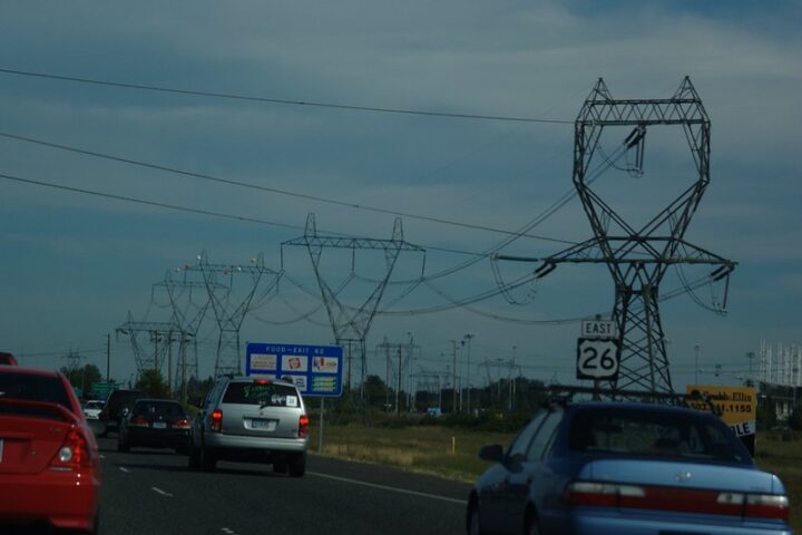 Highway with cars and high-voltage power transmission lines near Hillsboro, Oregon, illustrating U.S. infrastructure amid rising electricity demand.