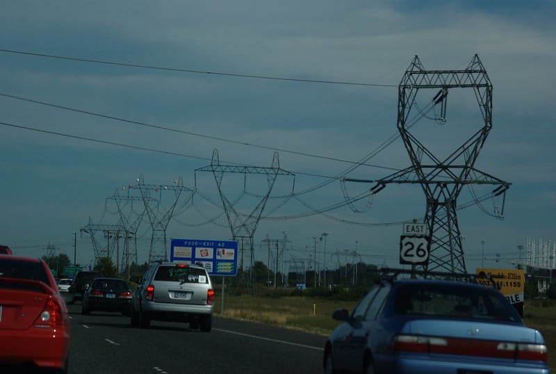 Highway with cars and high-voltage power transmission lines near Hillsboro, Oregon, illustrating U.S. infrastructure amid rising electricity demand.