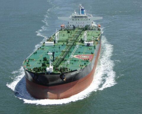Large green and red oil tanker ship sailing through blue ocean waters