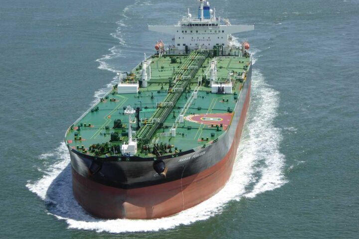 Large green and red oil tanker ship sailing through blue ocean waters