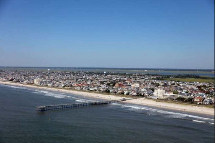 Aerial photograph of Ventnor City, New Jersey shoreline showing beach, ocean waves, residential buildings, and a fishing pier extending into the Atlantic Ocean, taken in 2017.