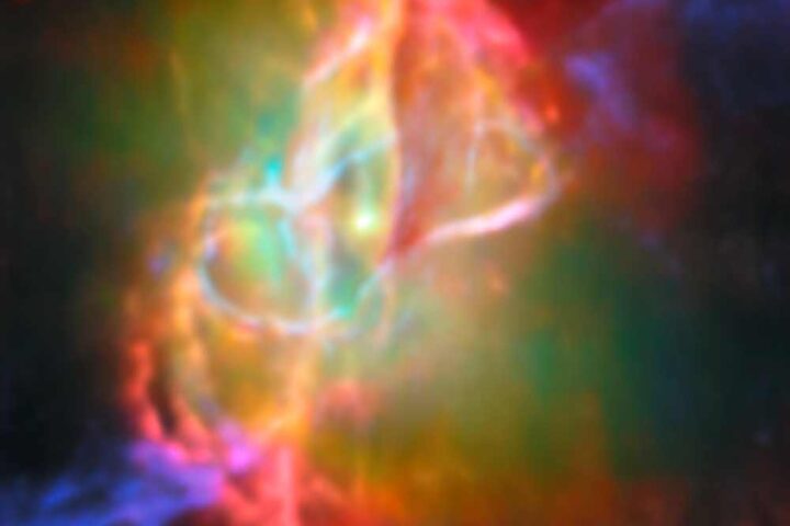 Colorful infrared image of the Butterfly Nebula's center showing a bright central star surrounded by greenish nebulosity and looping structures in cream, orange, and pink colors, captured by Webb telescope and ALMA.