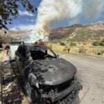 Smoke from the Willard Peak Fire above North Ogden, Utah, with foothills visible and haze affecting nearby neighborhoods.