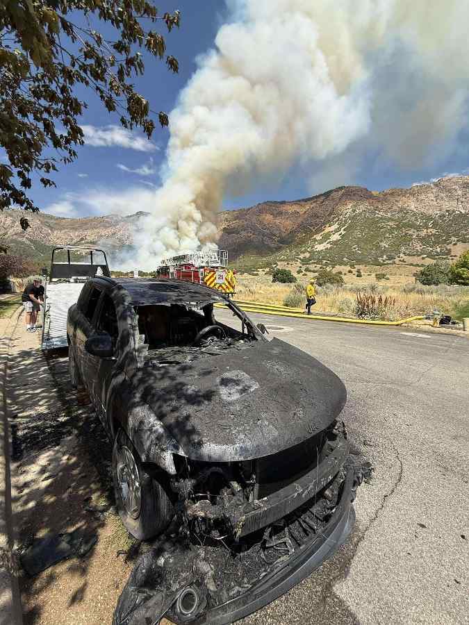 Smoke from the Willard Peak Fire above North Ogden, Utah, with foothills visible and haze affecting nearby neighborhoods.