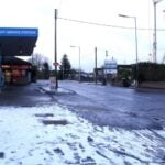 Snow-dusted pavement and a service station on Hillsborough Road, Carryduff, under overcast skies.