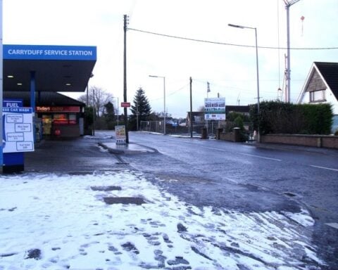 Snow-dusted pavement and a service station on Hillsborough Road, Carryduff, under overcast skies.