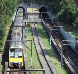 Aerial view of the unfinished Woollahra Station site showing train tracks, platform foundations, and surrounding vegetation between tunnels on Sydney's Eastern Suburbs railway line.