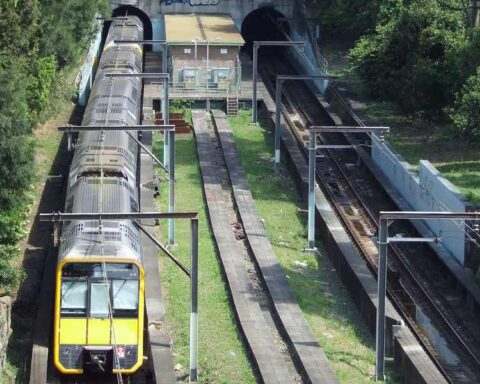 Aerial view of the unfinished Woollahra Station site showing train tracks, platform foundations, and surrounding vegetation between tunnels on Sydney's Eastern Suburbs railway line.