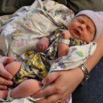 Newborn baby cradled gently in an adult’s hands