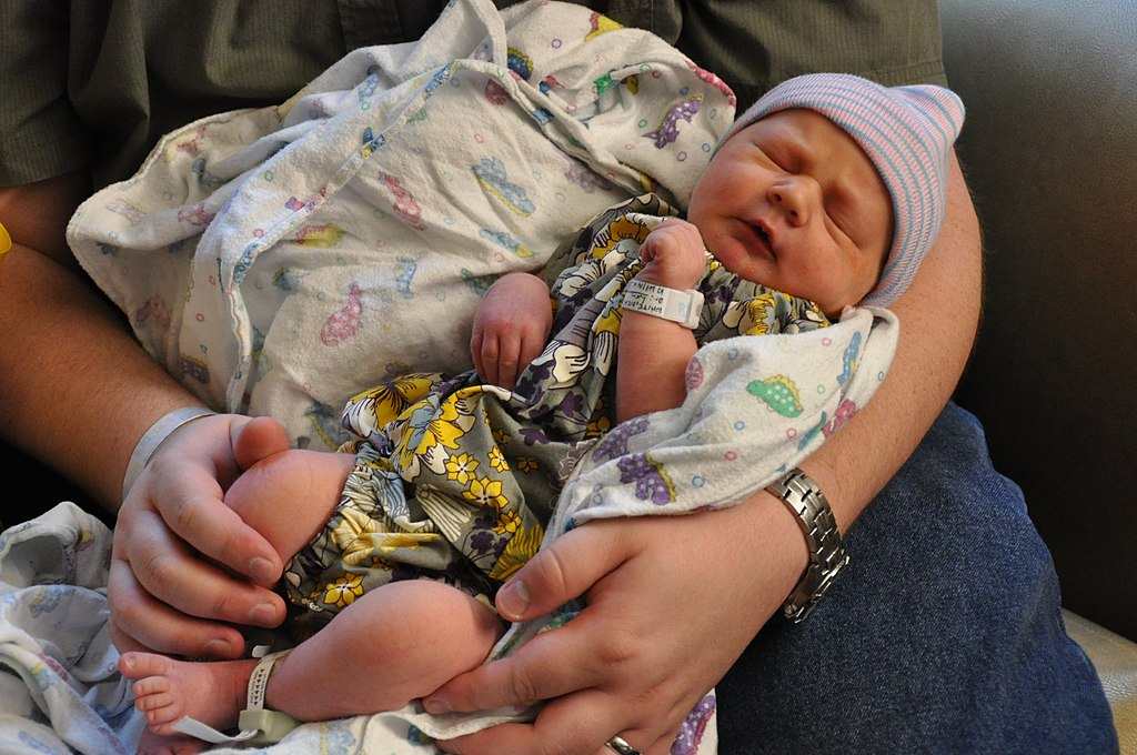 Newborn baby cradled gently in an adult’s hands