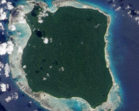 Satellite view of North Sentinel Island in the Andaman Sea, showing forested land surrounded by coral reefs and turquoise waters.