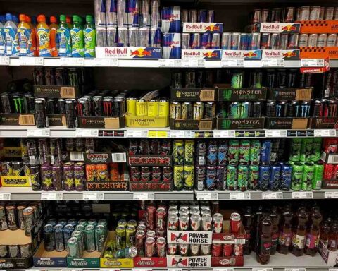 Rows of assorted energy drink cans on supermarket shelves.