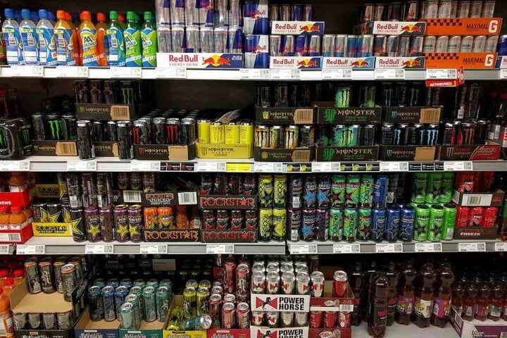 Rows of assorted energy drink cans on supermarket shelves.