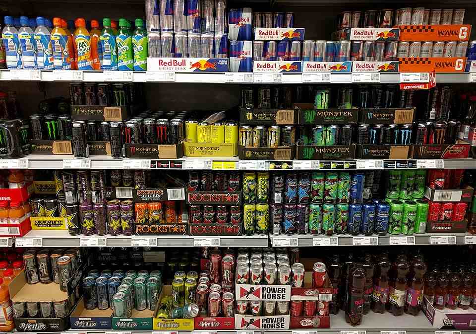 Rows of assorted energy drink cans on supermarket shelves.