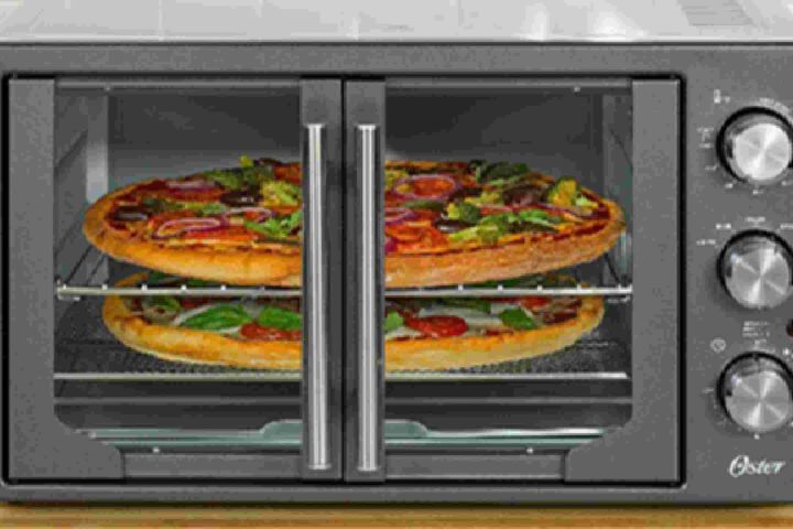 Oster French Door Countertop Oven model TSSTTVFDMAF with stainless steel finish, featuring center-opening glass doors and control knobs on the right side, shown cooking multiple pizzas on two racks.