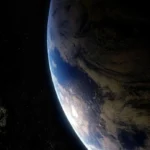 Asteroid approaching Earth against the black background of space, with the blue planet visible in the frame.