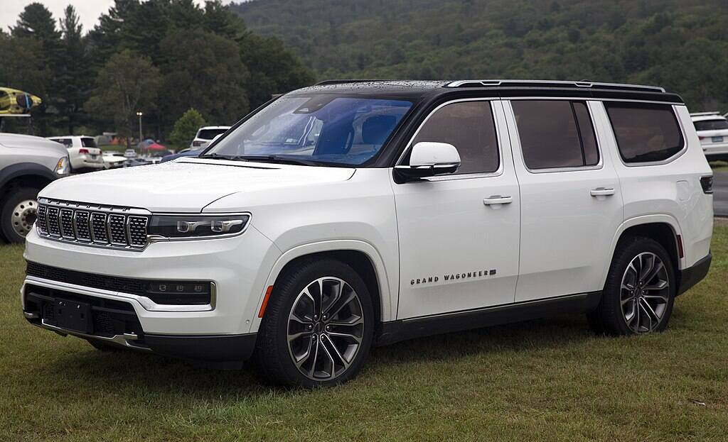 White 2022 Jeep Grand Wagoneer Series III SUV parked on grass at an outdoor showcase.