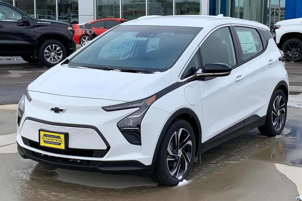 White 2022 Chevrolet Bolt EV compact electric vehicle parked in a dealership lot with other cars visible in the background