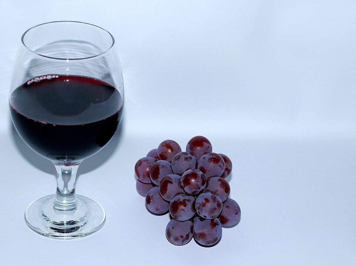 A glass of red wine next to a small bunch of purple grapes (CC BY-SA 3.0)
