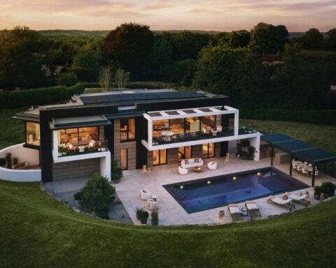 Drone view of Omaze’s £4 million eco-friendly prize house in Surrey Hills with modern architecture surrounded by woodland.