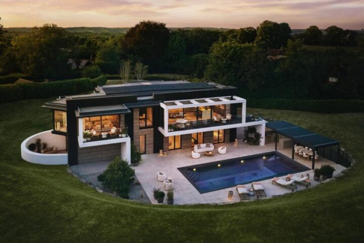 Drone view of Omaze’s £4 million eco-friendly prize house in Surrey Hills with modern architecture surrounded by woodland.