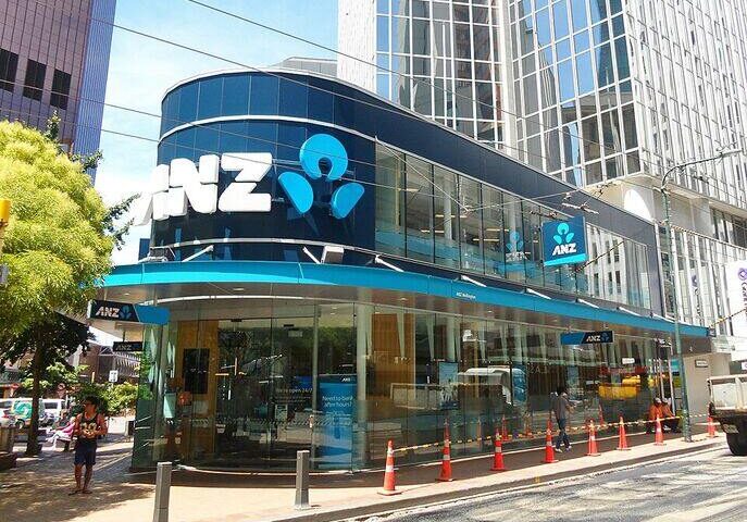 Street-level view of the ANZ Bank Tower on Lambton Quay in Wellington, New Zealand, showing a glass-fronted corner branch with the ANZ logo and pedestrians nearby.