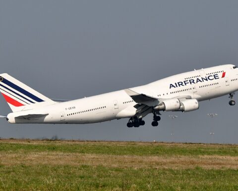 Air France Boeing 747-400M aircraft taking off from Paris-Charles de Gaulle Airport, with its distinctive red, white and blue livery visible against a cloudy sky.