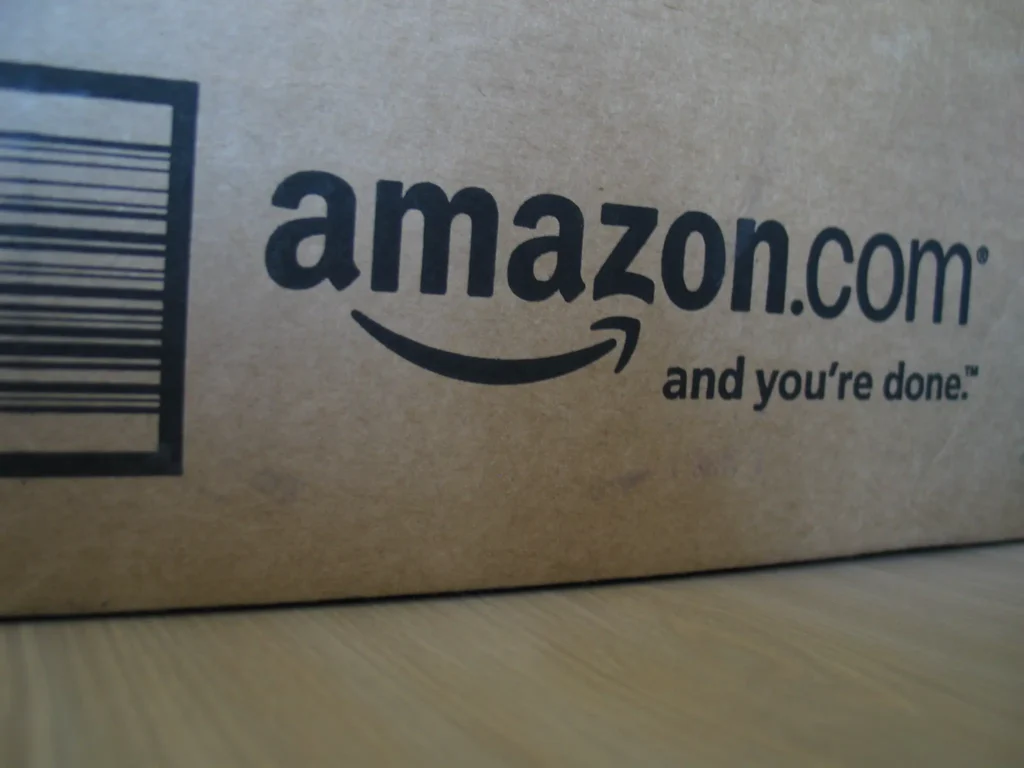 Close-up of an Amazon.com shipping box showing the company’s logo and slogan.
