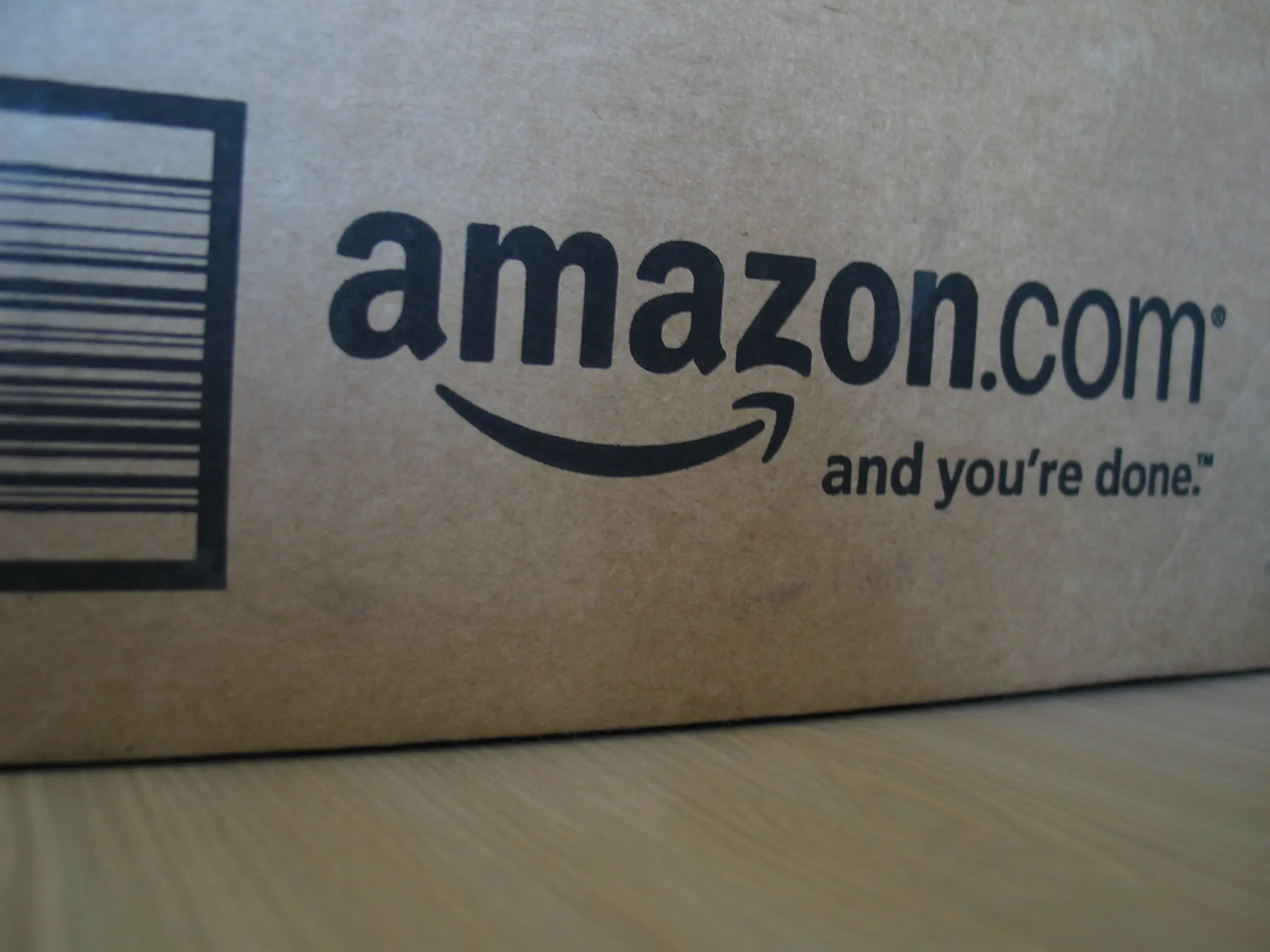 Close-up of an Amazon.com shipping box showing the company’s logo and slogan.