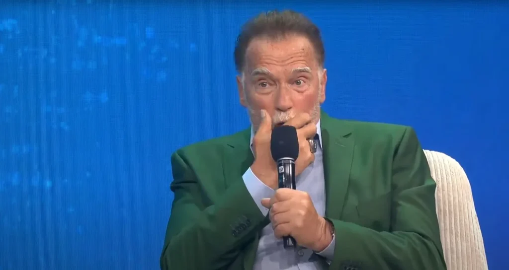 Arnold Schwarzenegger speaking into a microphone during a climate change panel on pollution, organized by the Tony Blair Institute for Global Change.