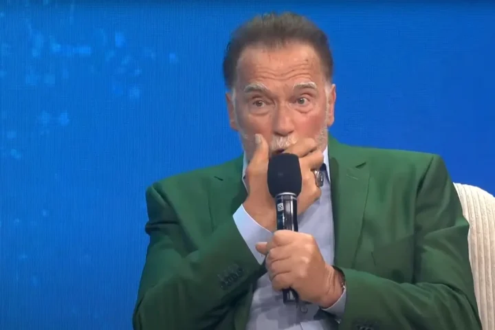 Arnold Schwarzenegger speaking into a microphone during a climate change panel on pollution, organized by the Tony Blair Institute for Global Change.