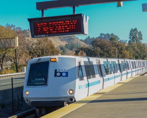 BART train pulling into Lafayette Station in California, photographed on a sunny day with hills in the background.