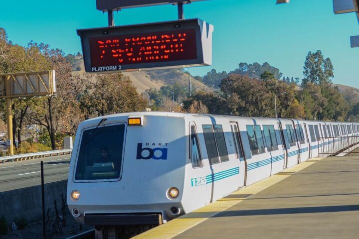BART train pulling into Lafayette Station in California, photographed on a sunny day with hills in the background.