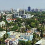 Aerial view of Bangalore skyline with high-rise buildings surrounded by dense green trees and residential areas.