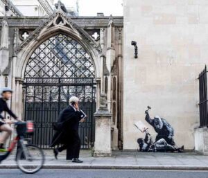 Banksy street art mural on the Royal Courts of Justice in London depicting a judge in a wig and gown striking a bloodied protester with a gavel.
