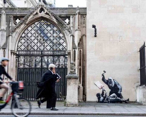 Banksy street art mural on the Royal Courts of Justice in London depicting a judge in a wig and gown striking a bloodied protester with a gavel.