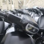 Row of black Ola Electric scooters parked in a manufacturing facility, showcasing streamlined design and readiness for distribution.