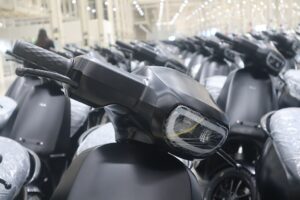 Row of black electric scooters in a manufacturing facility.