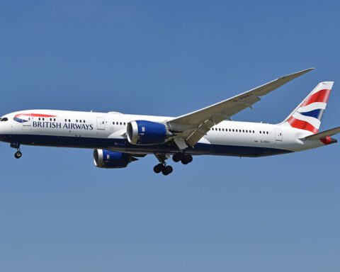 British Airways Boeing 787-9 Dreamliner with registration G-ZBKL in flight with landing gear down, featuring the airline's distinctive red, white and blue livery against a clear blue sky background