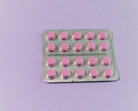 A blister pack of 20 small round pink medication tablets arranged in a grid pattern against a light purple background.