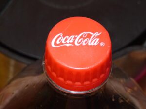 Close-up of a red Coca-Cola bottle cap on top of a plastic bottle against a dark background.