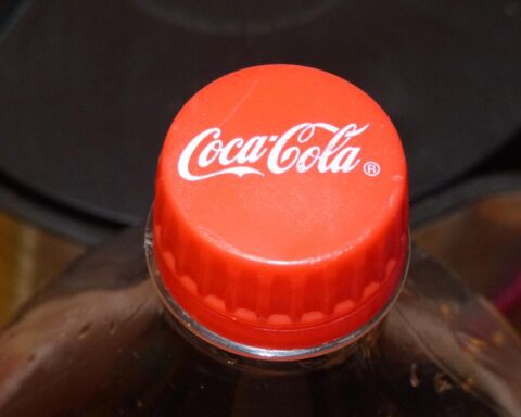 Close-up of a red Coca-Cola bottle cap on top of a plastic bottle against a dark background.