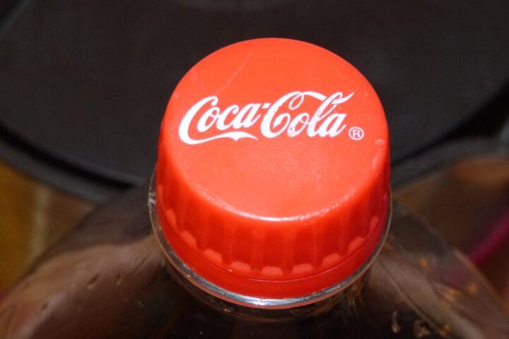 Close-up of a red Coca-Cola bottle cap on top of a plastic bottle against a dark background.