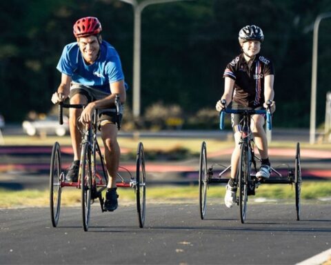 Two cyclists on adaptive bikes riding outdoors, representing community-focused health and sustainability initiatives supported by the Bupa Foundation.