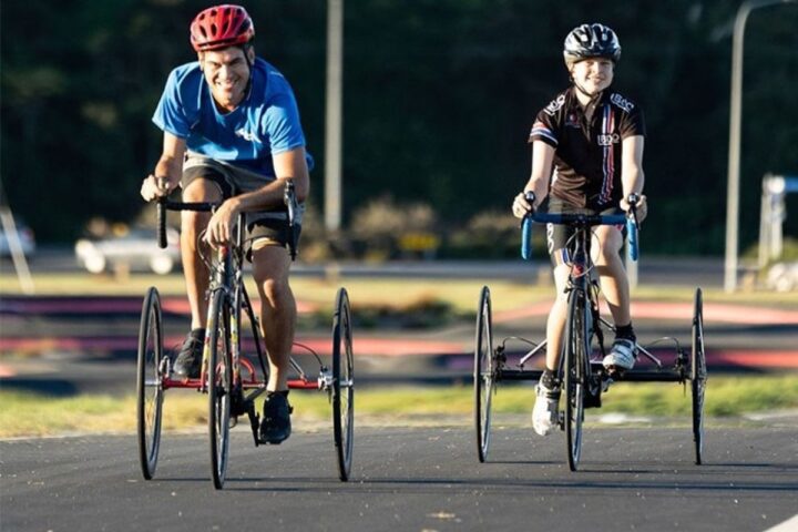 Two cyclists on adaptive bikes riding outdoors, representing community-focused health and sustainability initiatives supported by the Bupa Foundation.
