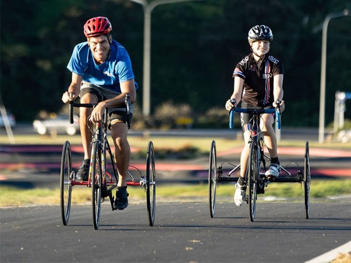 Two cyclists on adaptive bikes riding outdoors, representing community-focused health and sustainability initiatives supported by the Bupa Foundation.